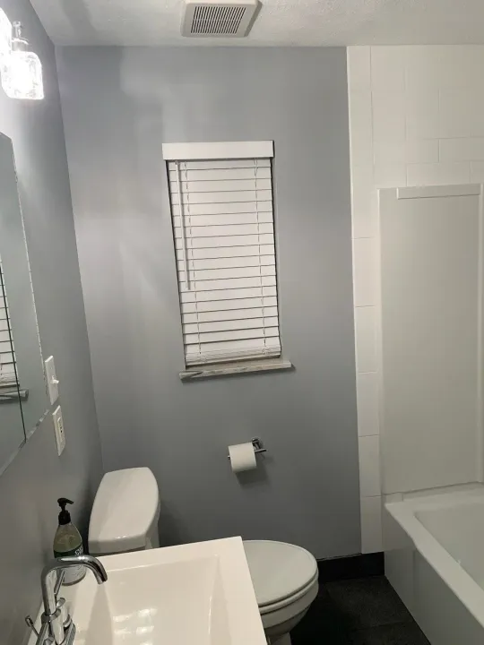 Small unfinished bathroom with black shower pan liner and white tiled walls