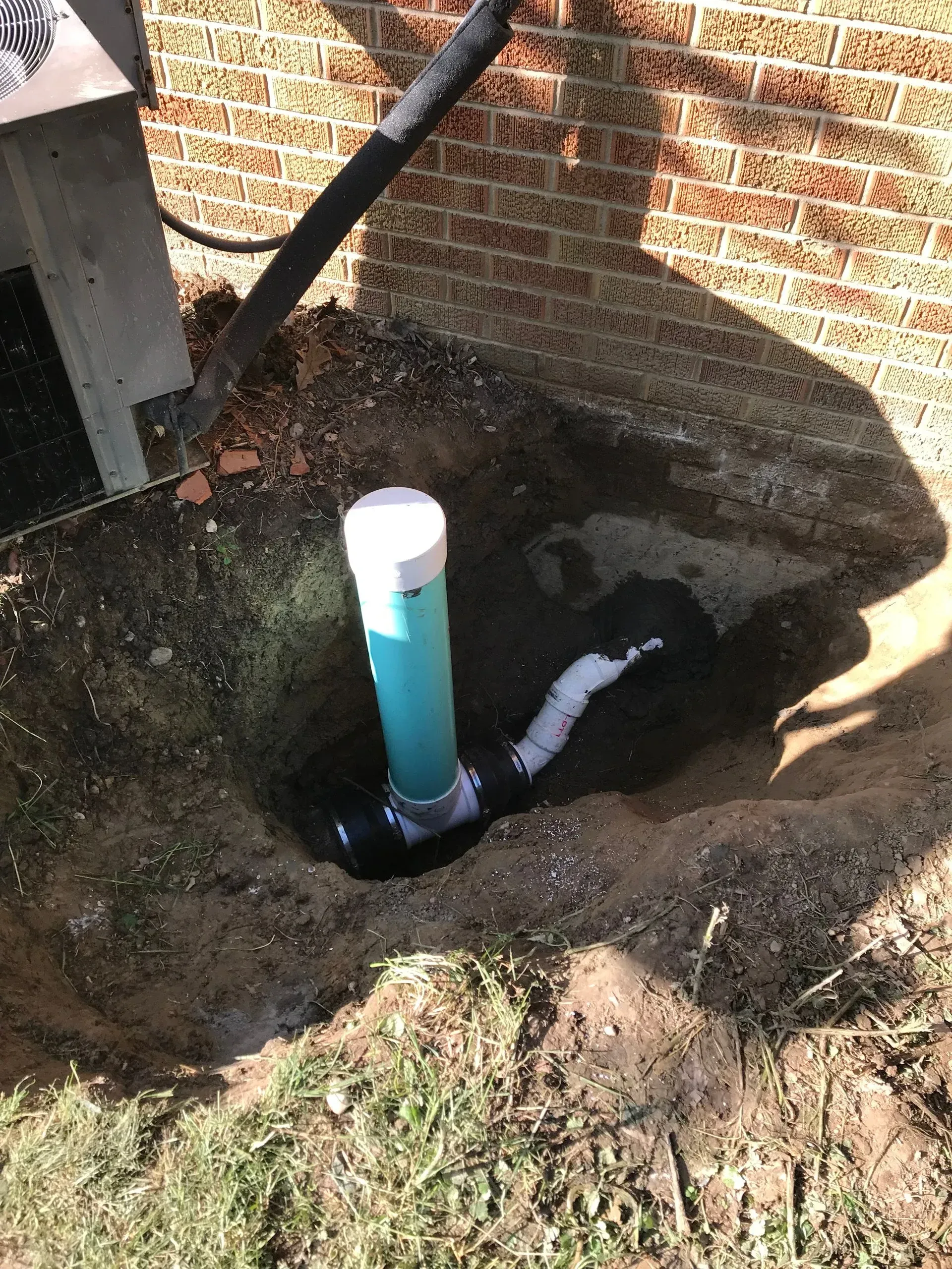 Plumbing excavation work in progress with exposed pipe and trench